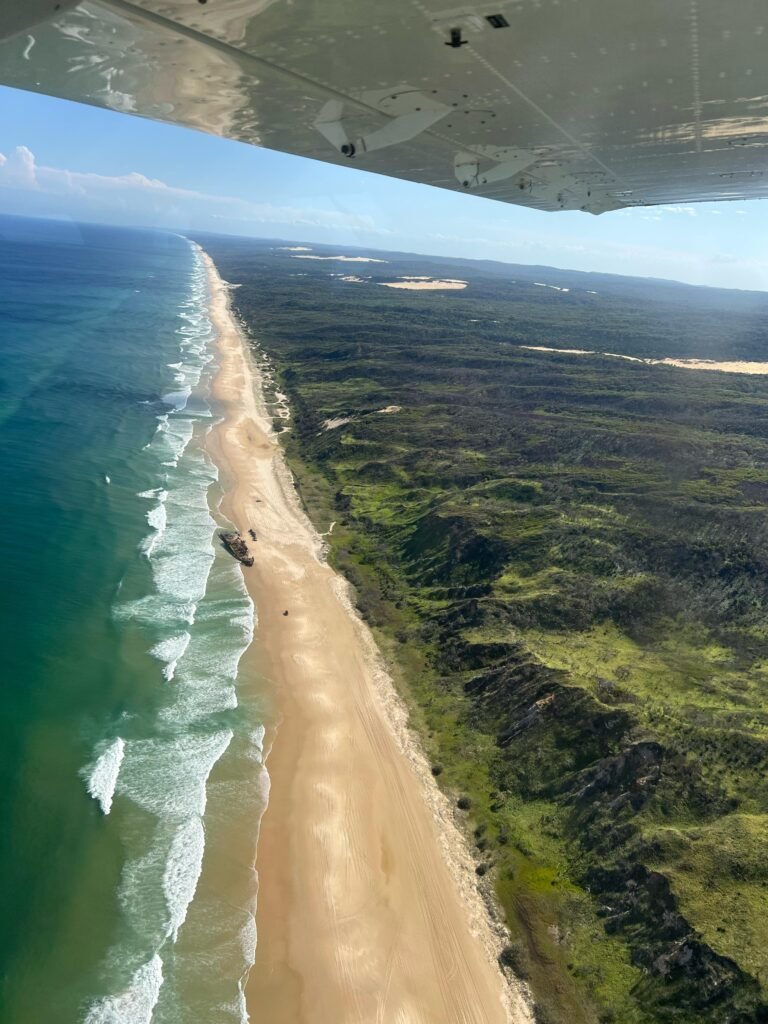 Aerial shot from a plan of the coastline of Fraser Island with views of the sea, beach and rainforest.