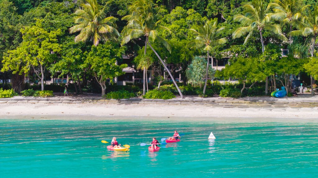 An image taken from sea of the Fitzroy Island shore. Picture are two people kayaking.