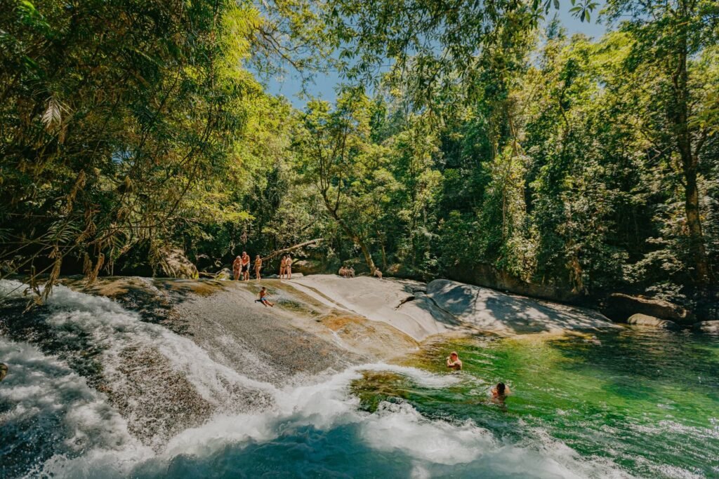 A child slides down the natural slide at Josephine Falls. Others wait their turn behind him.