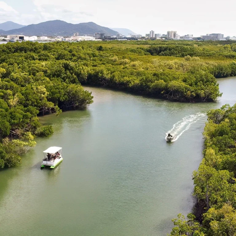 Aerial shot of a tinny boat and a jet ski cruising along the river on Trinity Inlet.