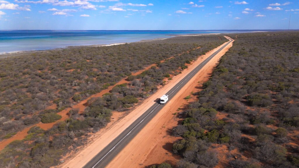 Birdseye view of a campervan driving along a road in the Outback.