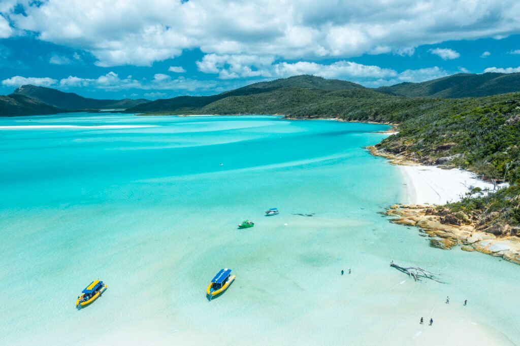 Aerial shot of a bay on the Whitsundays with rafting boats parked on the beach.