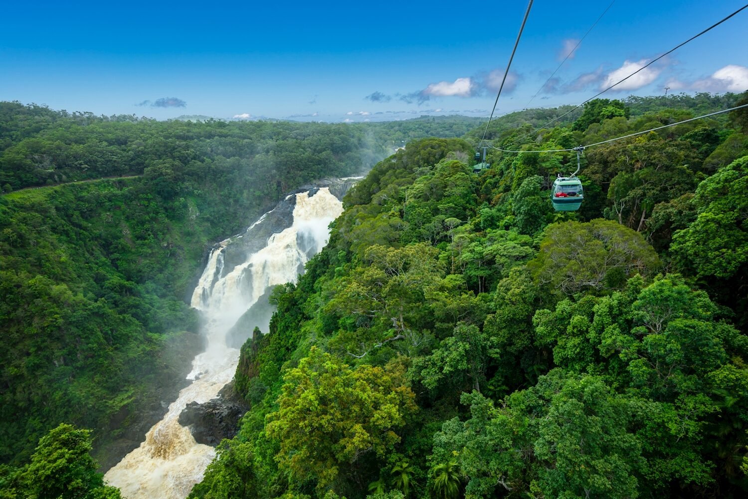 A panoramic shot of the skyrail going across the rainforest and waterfall in Kuranda.