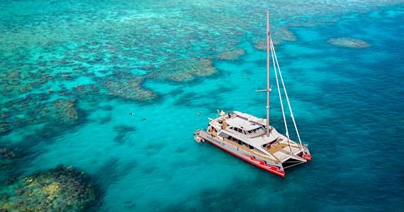 Wide shot of Passions of Paradise boat floating in the water near coral formations on a Great Barrier Reef tour.