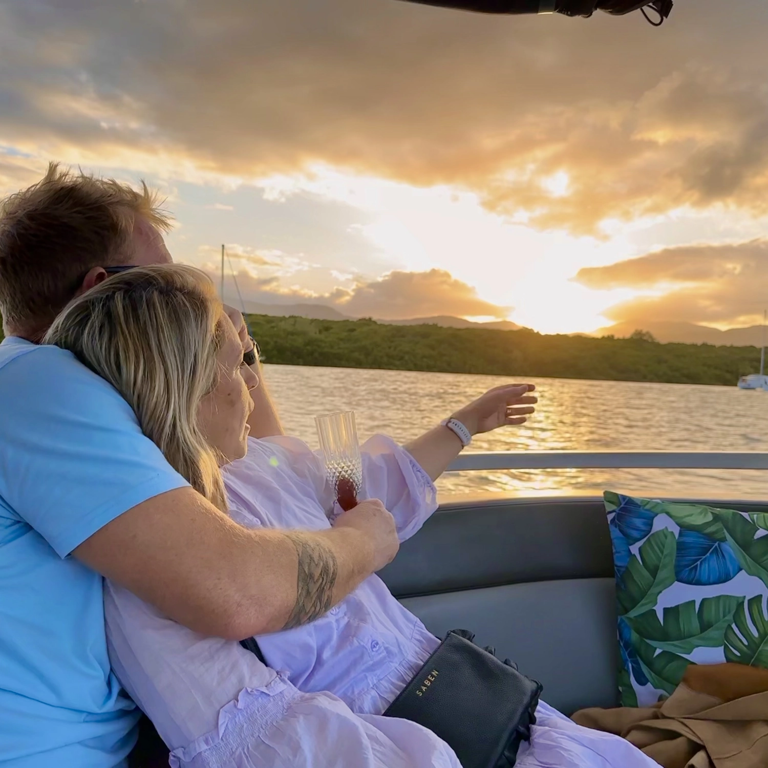 A man and a woman cuddled up to each other whilst watching the sunset on a river cruise in Cairns.