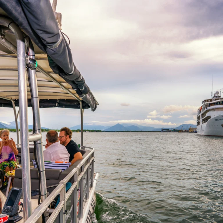A wide shot of the river cruise boat out in the water with a bigger boat in the distance.