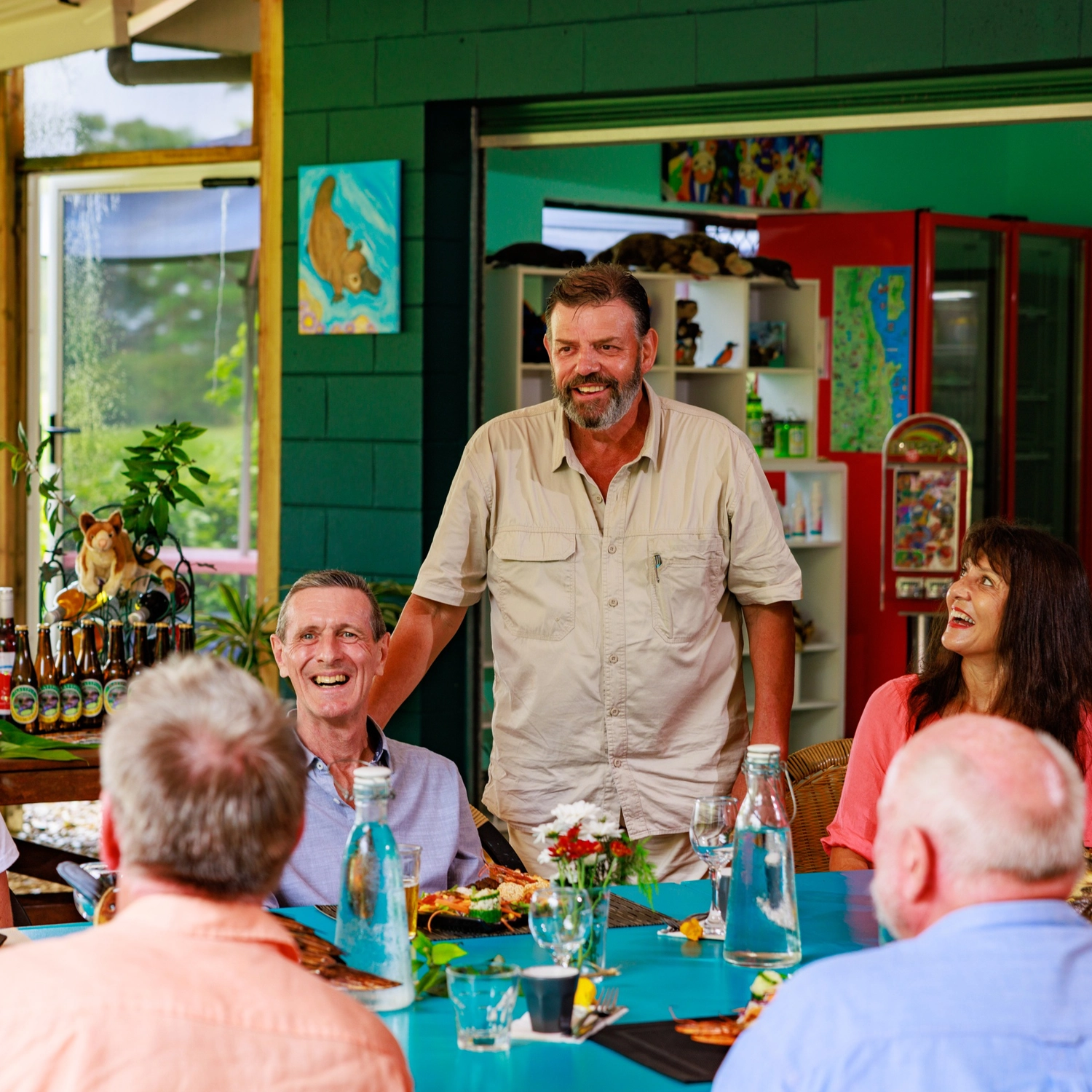 Tour guide laughing with four tourists sat down at a table on an Australian food tour.
