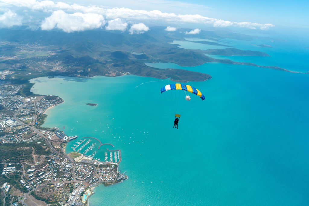 Two people with a parachute flying above the skies of a city
