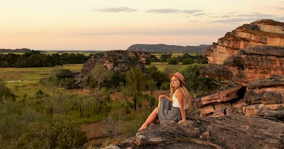 A female sitting on a rock looking at in the distance on a northern territory group tour.