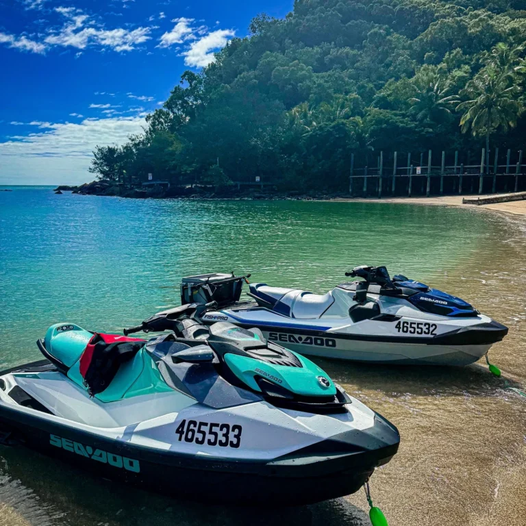 Two jet skis parked up on the beach on a jet ski tour.