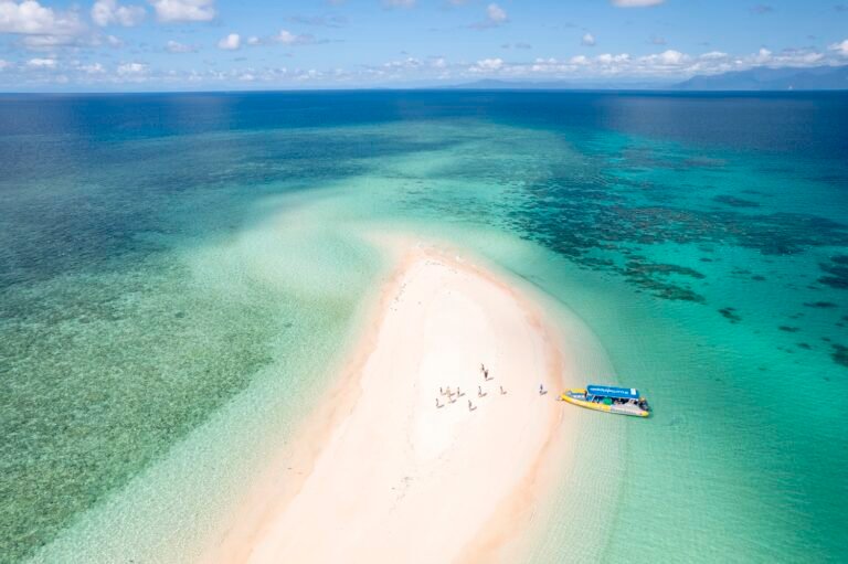 Image shows a rafting boat parked on a sand cay in the middle of the ocean.