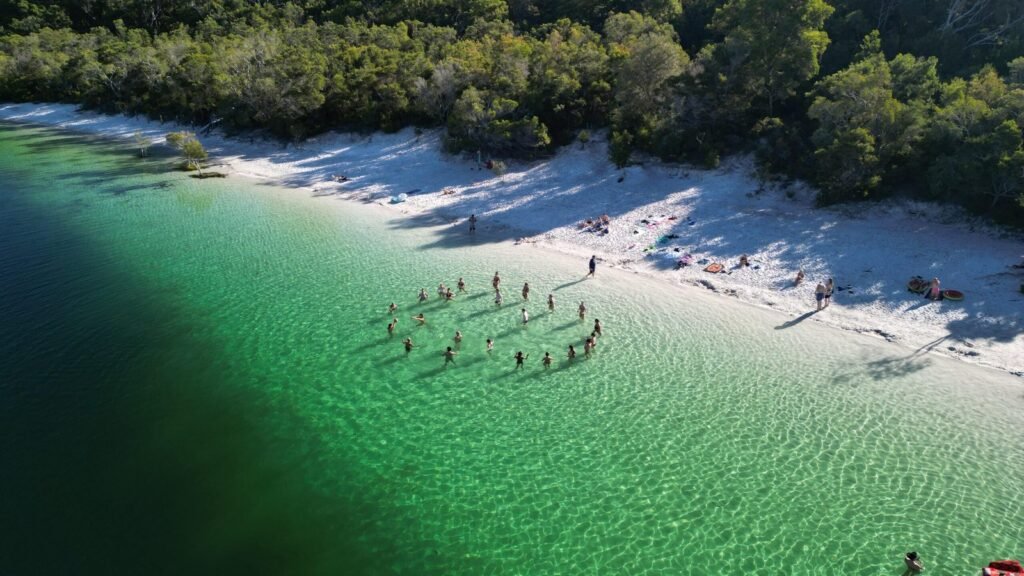 Aerial shot of Lake Mackenzie on Fraser Island with people stood in a circle in the water.