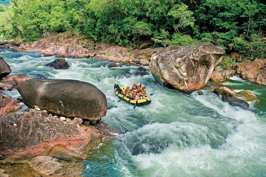 Wide shot of a rafting boat coming down a rapid on Tully River