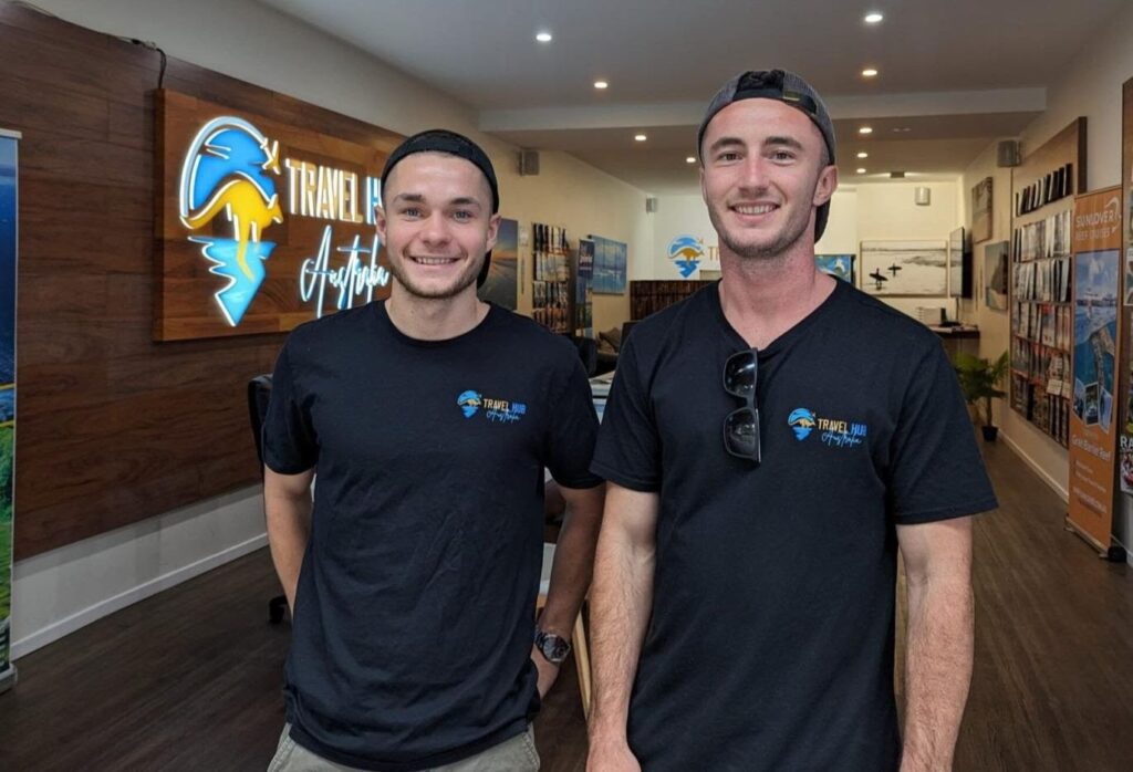 Two founders of Travel Hub stood side by side outside of the Travel Hub shop.