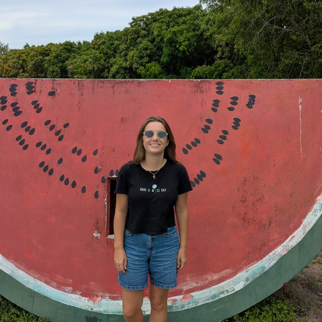 A woman standing in front of a watermelon sign.